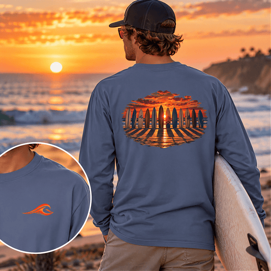 Man wearing the FLOWAV Coastal Sunset Long Sleeve Tee in blue jean looking out over ocean while holding a surfboard