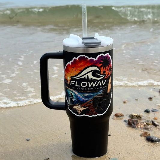 Black tumbler with FLOWAV Sunset vinyl sticker on the beach with ocean waves in the background