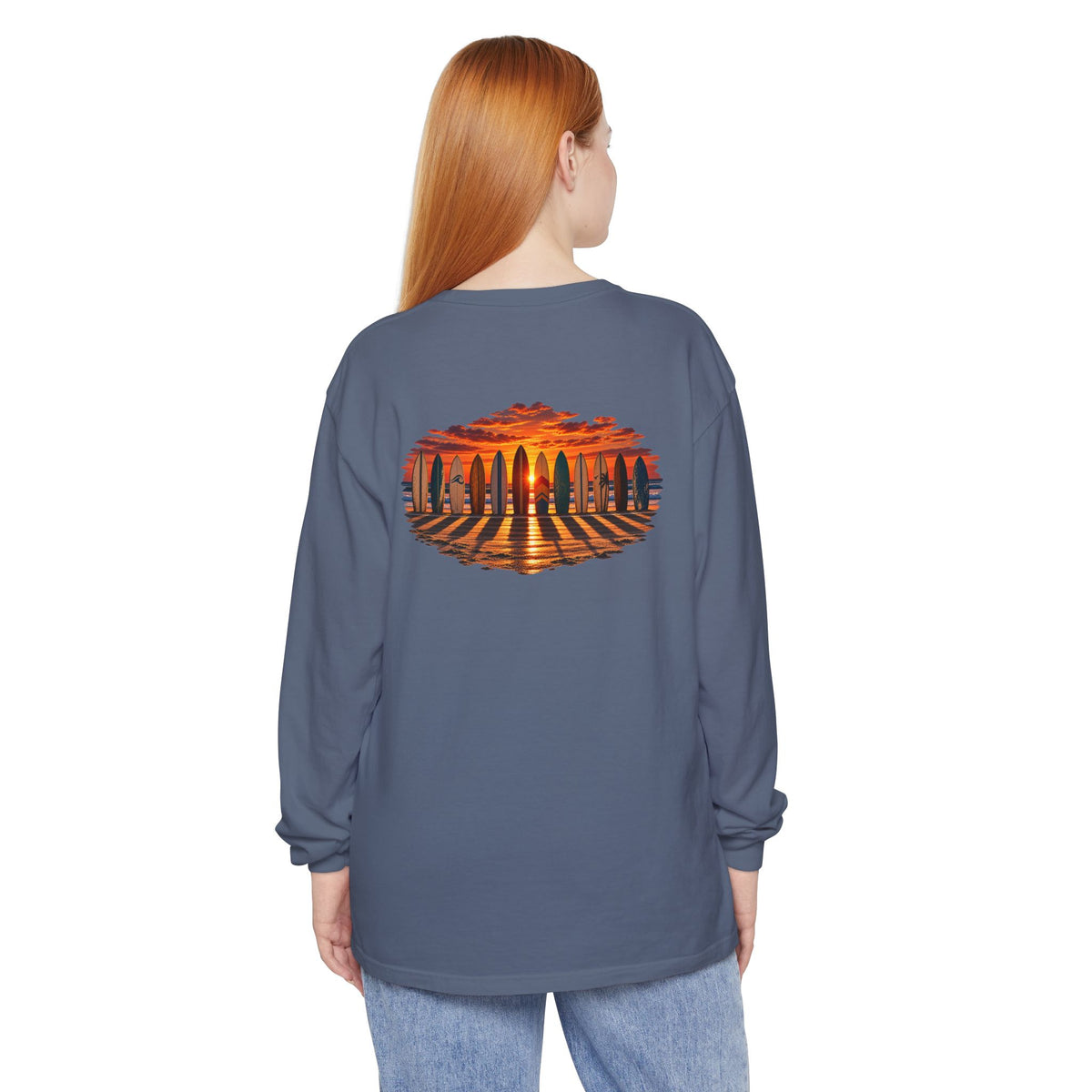 Woman wearing the FLOWAV Coastal Sunset Long Sleeve Tee in blue jean showing the back surfboard and piano keys at sunset