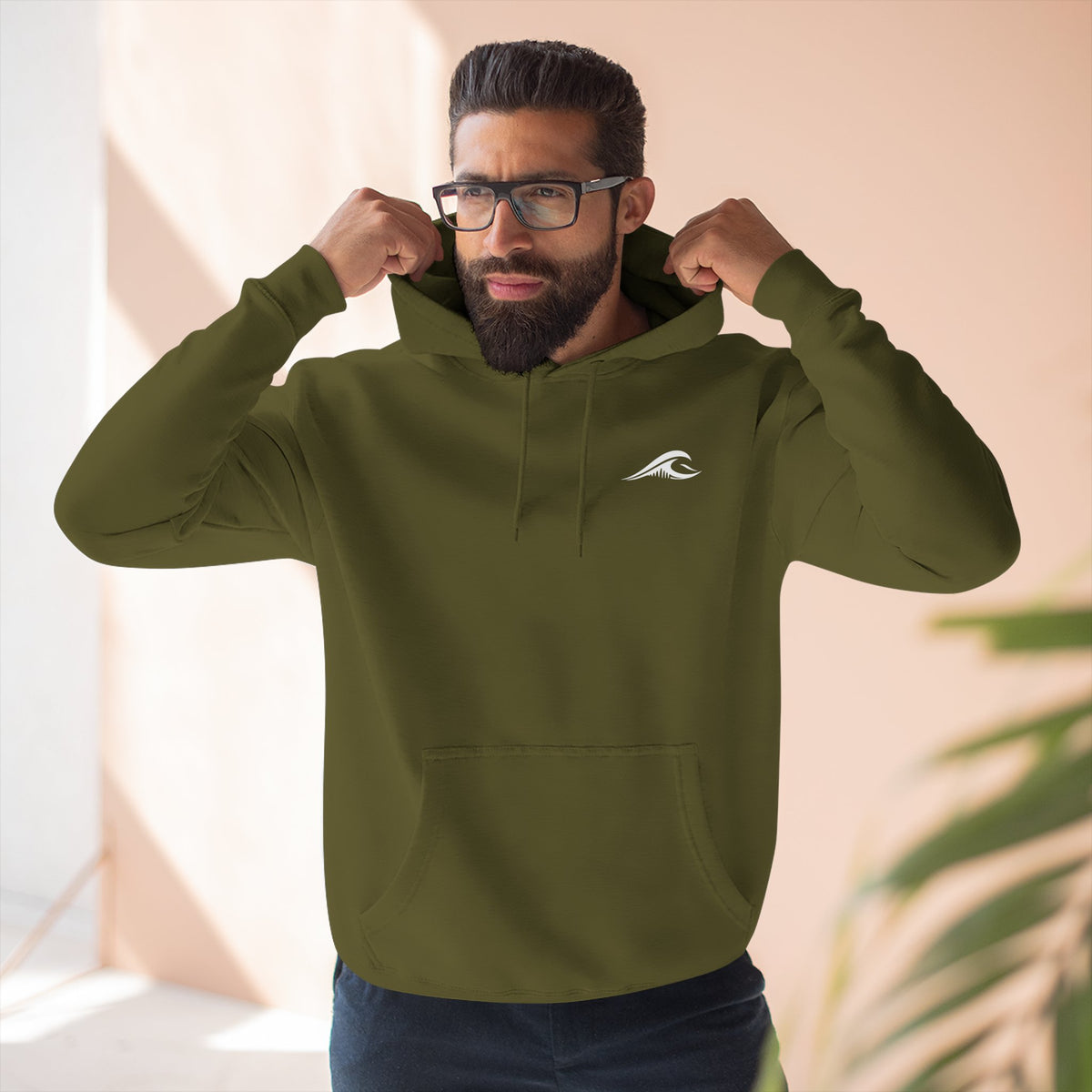 Man wearing the FLOWAV Coastal Graphic Hoodie in army green showing the front wave logo on the left chest.
