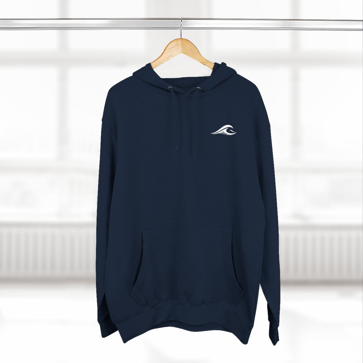 FLOWAV Coastal Graphic Hoodie in navy hanging on a wooden hanger showing the front wave logo