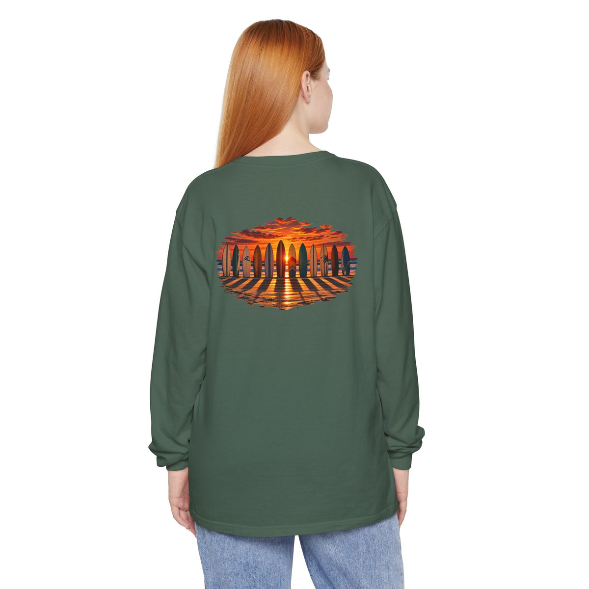 Woman wearing the FLOWAV Coastal Sunset Long Sleeve Tee in blue spruce showing the back surfboard and piano keys at sunset