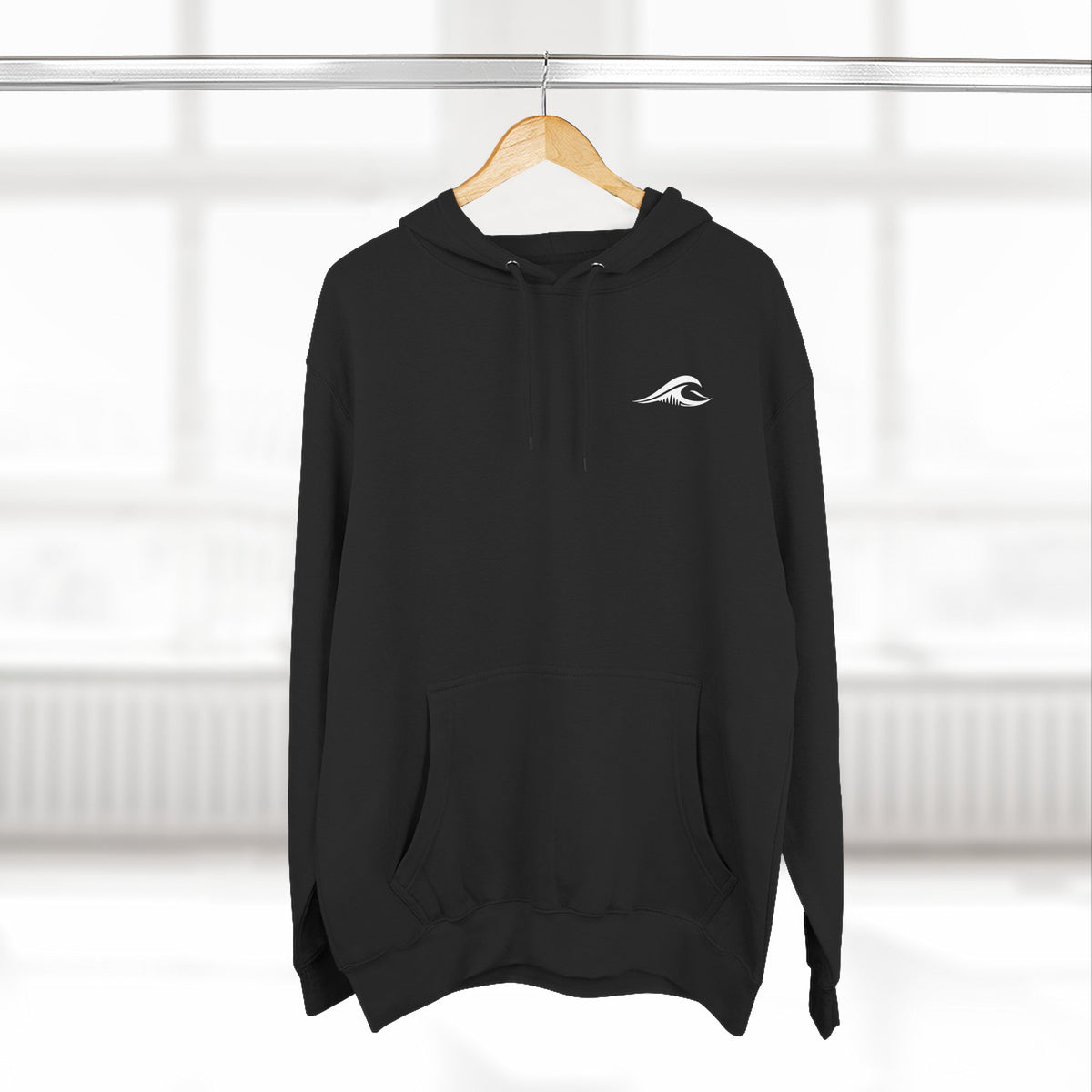 FLOWAV Coastal Graphic Hoodie in black hanging on a wooden hanger showing the front wave logo