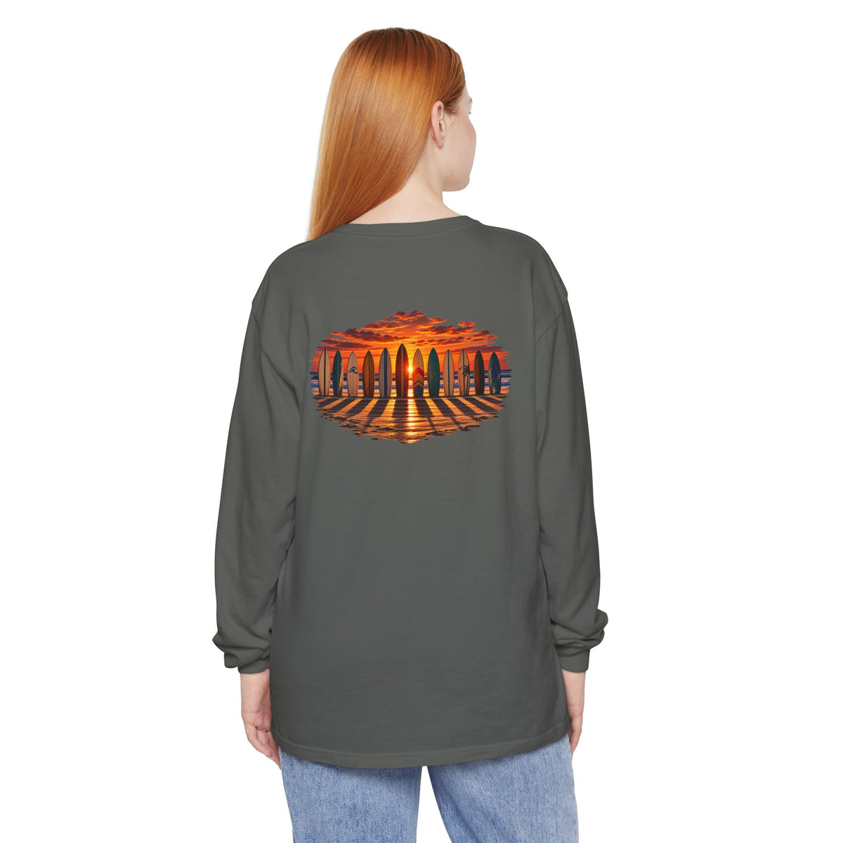 Woman wearing the FLOWAV Coastal Sunset Long Sleeve Tee in pepper showing the back surfboard and piano keys at sunset