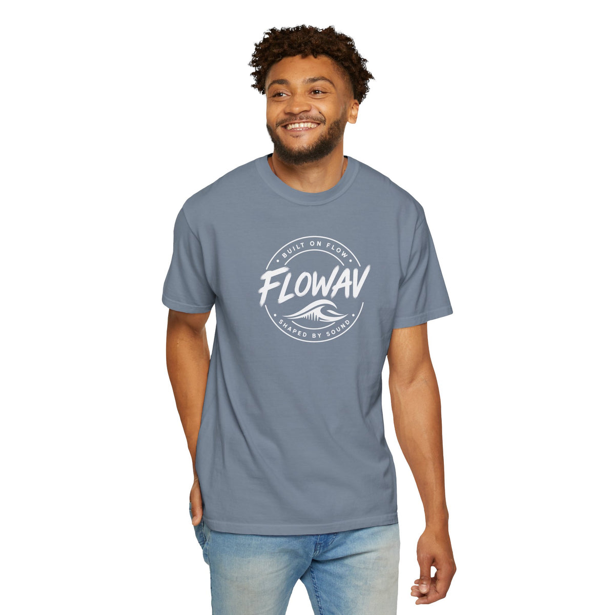 A man wearing the FLOWAV Coastal Badge Tee in blue jean showing the front badge graphic.