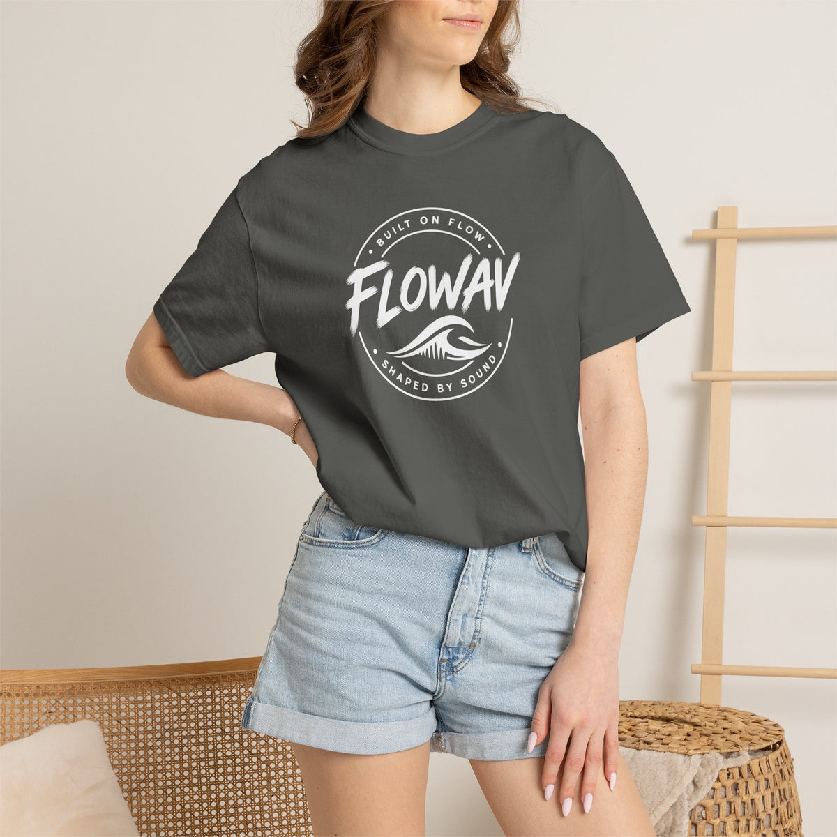 A woman wearing the FLOWAV Coastal Badge Tee in pepper showing the front coastal graphic and built on flow shaped by sound.