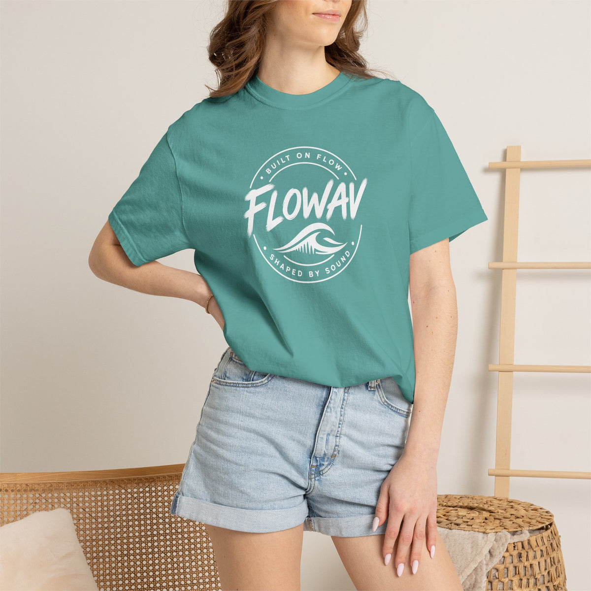 A woman wearing the FLOWAV Coastal Badge Tee in seafoam showing the front coastal graphic and built on flow shaped by sound.