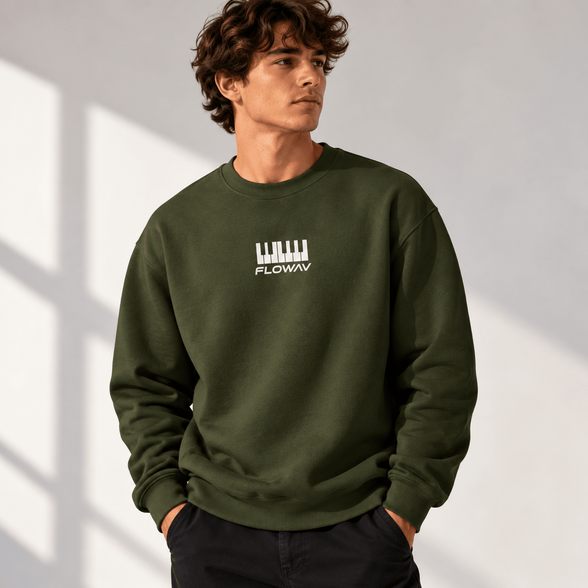 Man with long wavy hair wearing the FLOWAV Keys Crewneck Sweatshirt in army showing the front piano keys graphic and FLOWAV wordmark.