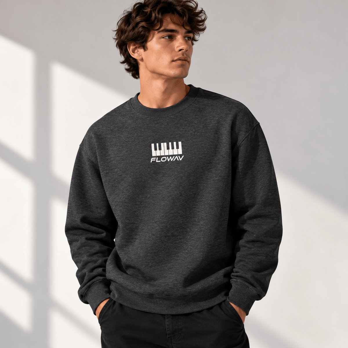 Man with long wavy hair wearing the FLOWAV Keys Crewneck Sweatshirt in charcoal heather showing the front piano keys and wordmark graphic