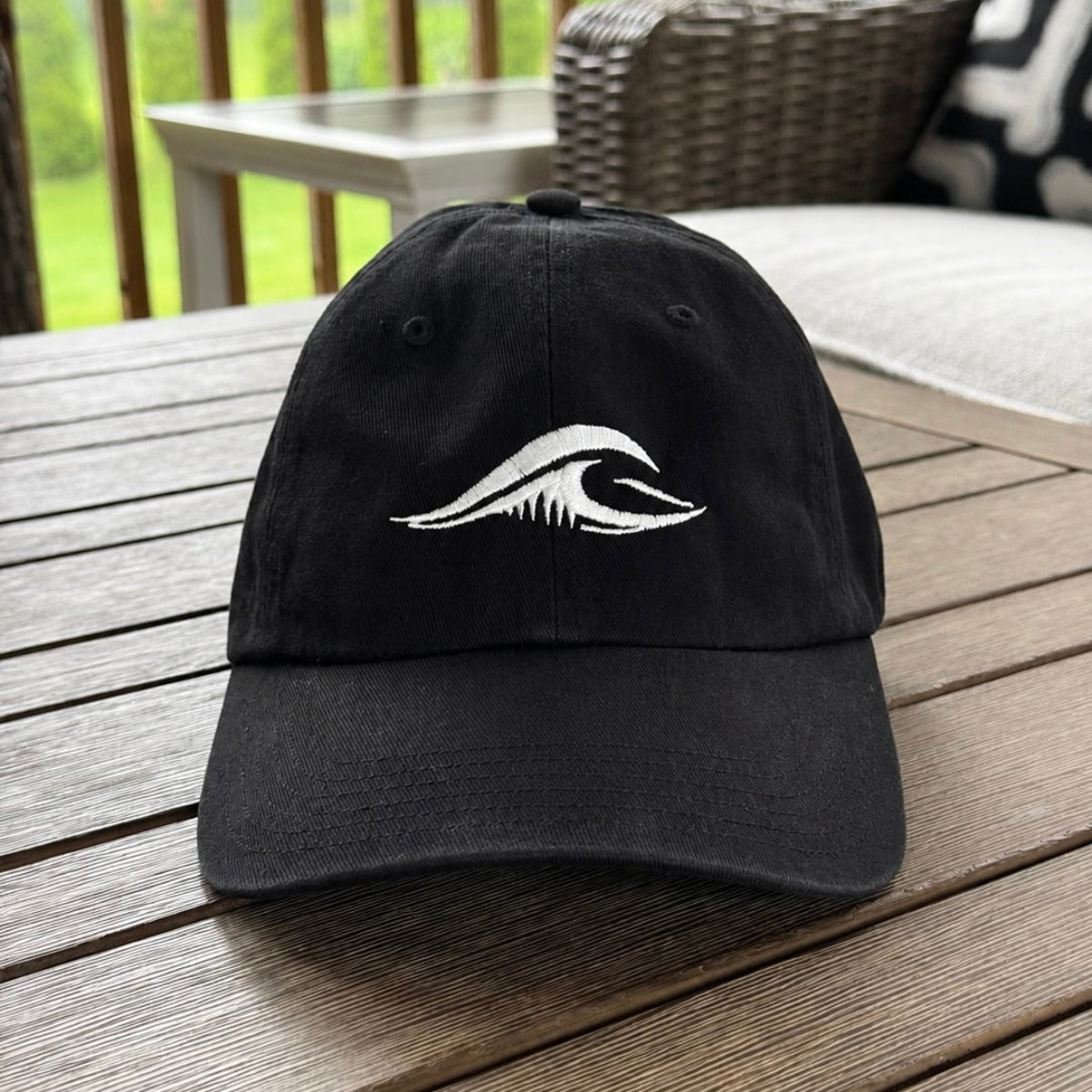 FLOWAV Richardson R55 classic black baseball hat with cream embroidered wave logo displayed on an outdoor table