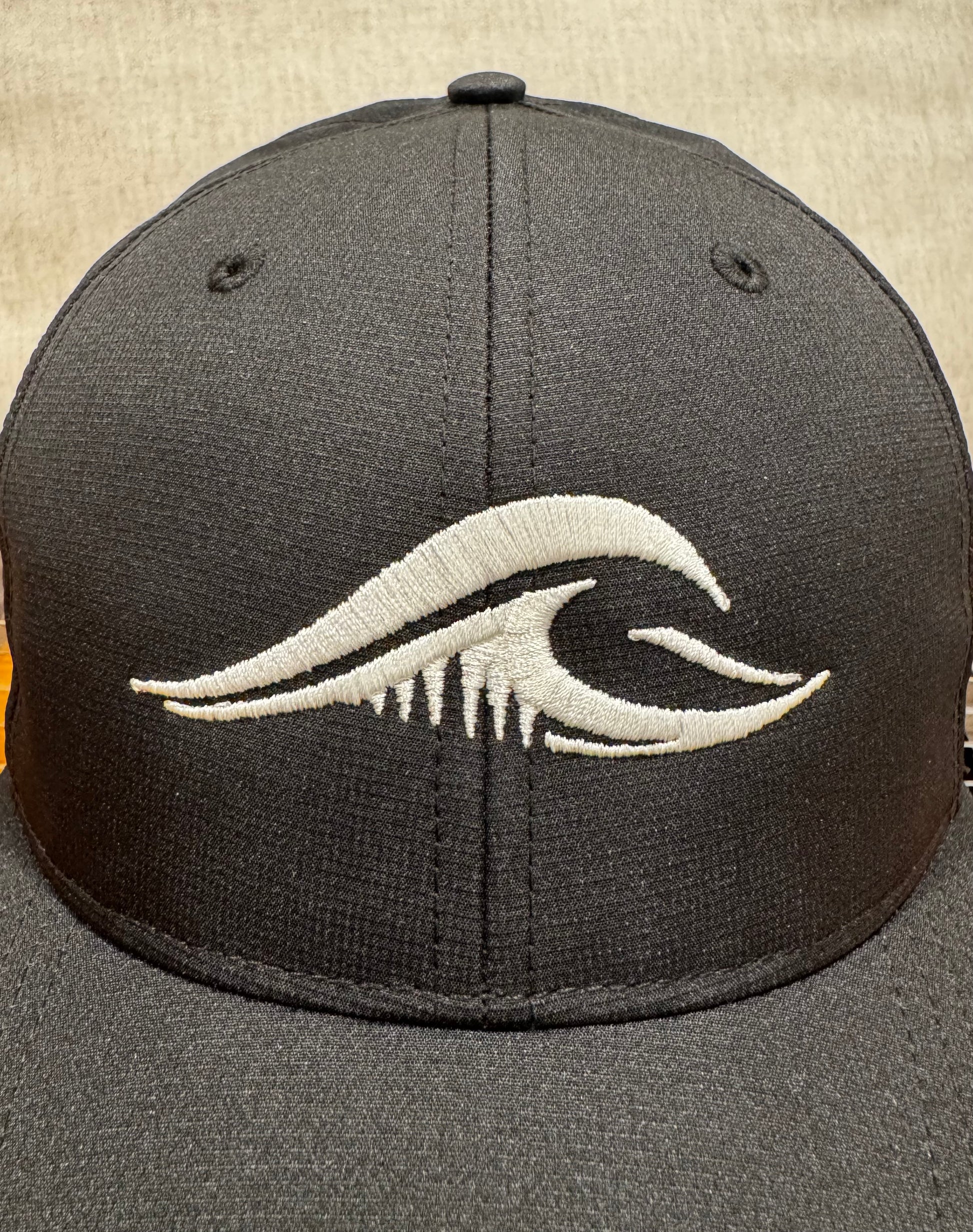 Front view of the black FLOWAV Richardson R25 Performance Hat with embroidered cream wave logo