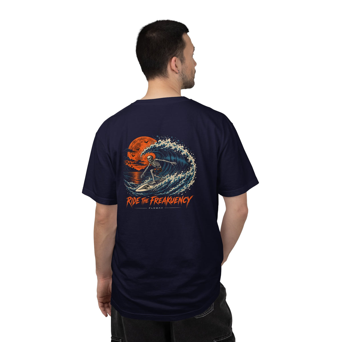 A man wearing the FLOWAV Ride the Freakuency Graphic Tee in True Navy showing the back skeleton surfer graphic
