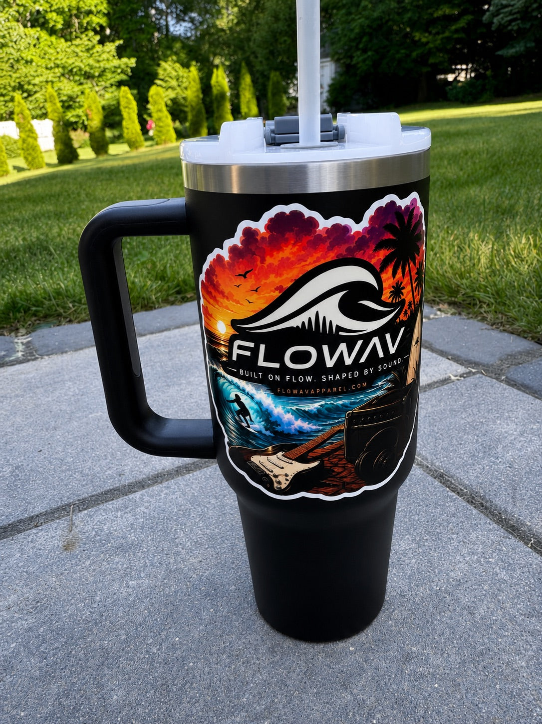 FLOWAV Sunset Sticker applied to a black insulated tumbler outdoors