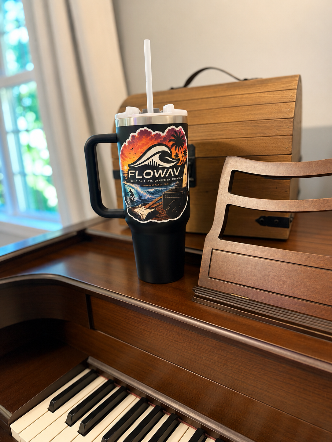 FLOWAV Sunset Sticker on a tumbler beside a piano and music equipment